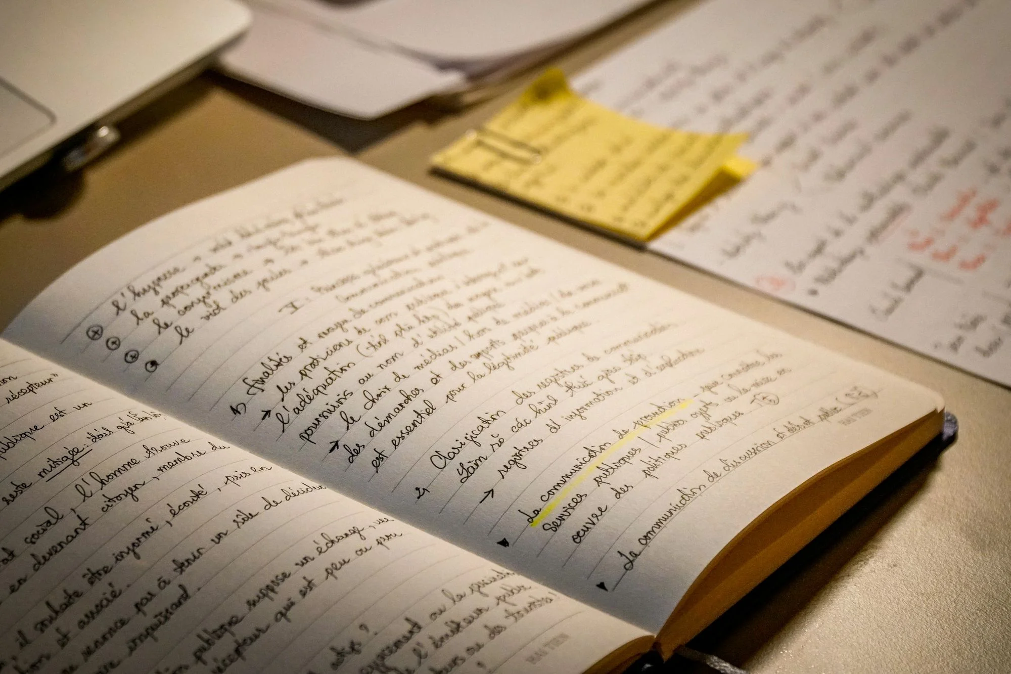 Open lined notebook with handwritten French study notes on warm paper