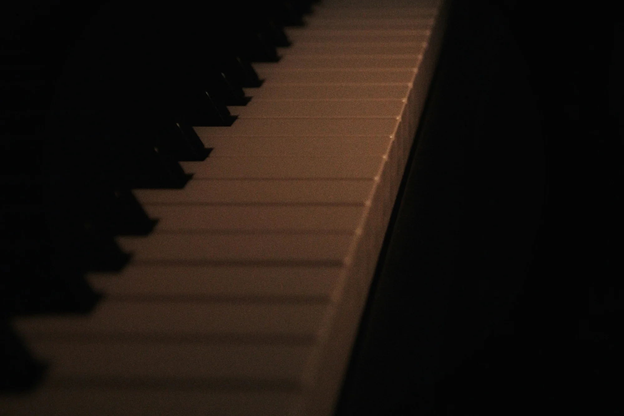 Diagonal piano keys in warm light against a dark background